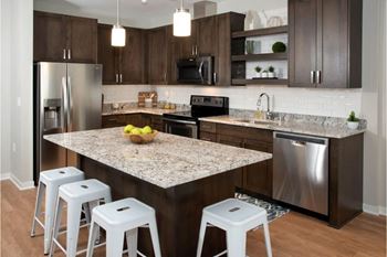 A kitchen with a granite countertop and white stools.